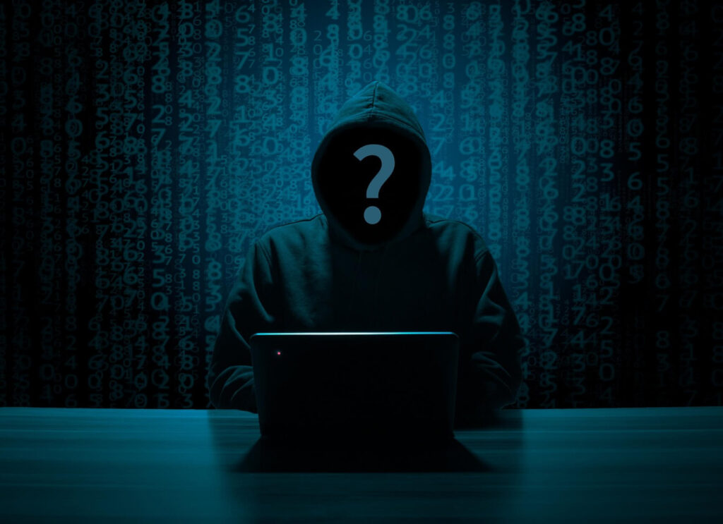 hooded mysterious man hacking with a computer