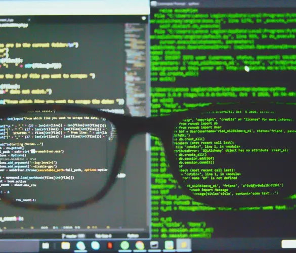 close-up view through the lens of a pair of glasses focusing on a computer screen displaying lines of code over a dark background