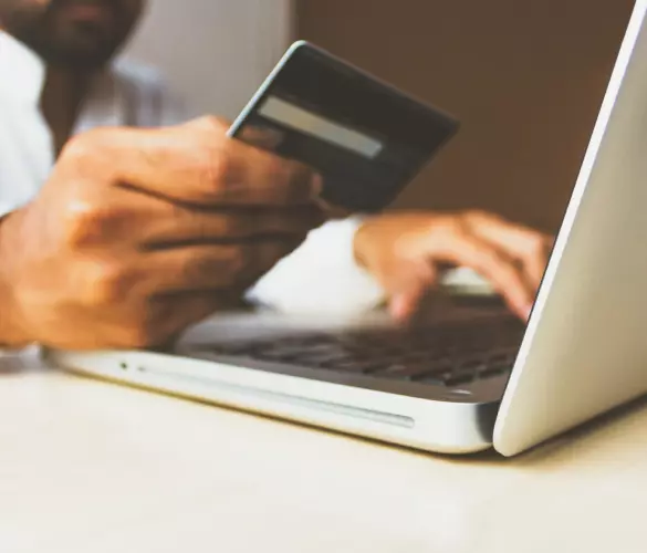 man holding credit card while shopping online