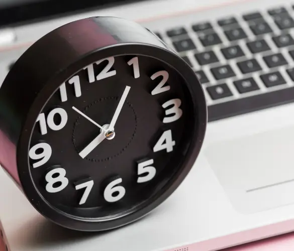 a small analog clock on top of a laptop