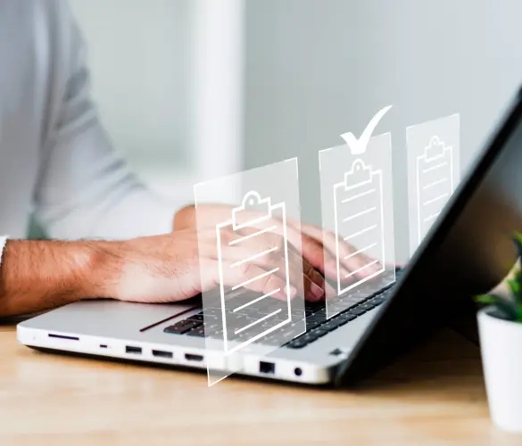 A man using a Macbook in a white office space with illustrations of web forms floating over the keyboard