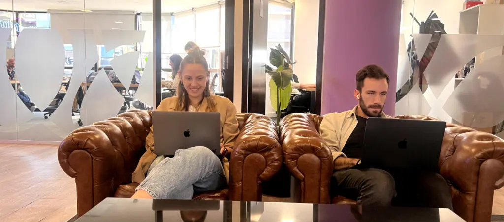 two team members from a WordPress development agency sitting side by side, each using their laptop