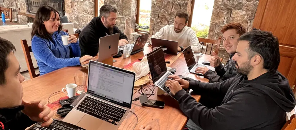 a team of wordpress developers, quality assurance analysts, and content creators gathered around a table, each working in a laptop