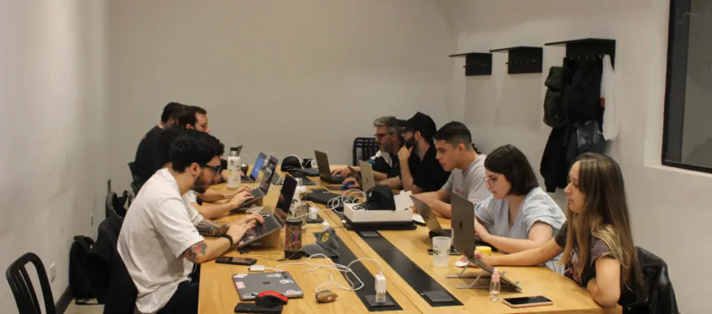 a group of team members working on a WordPress development project. They're all sitting around the same large table and each is using their own computer