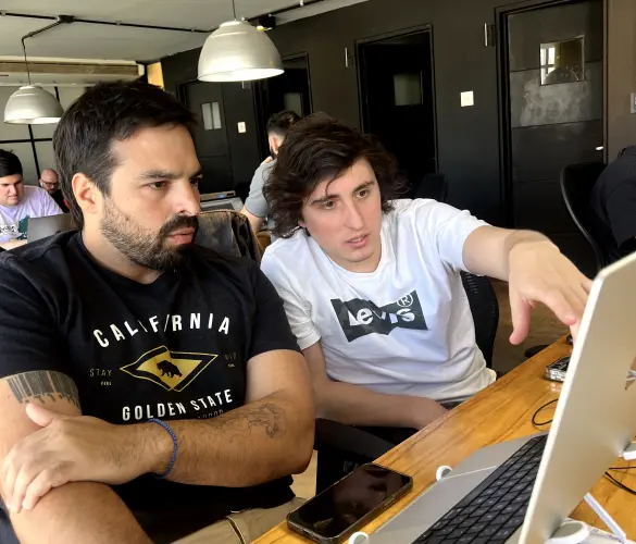 two WordPress developers sitting next to each other in front of a laptop while working on a website