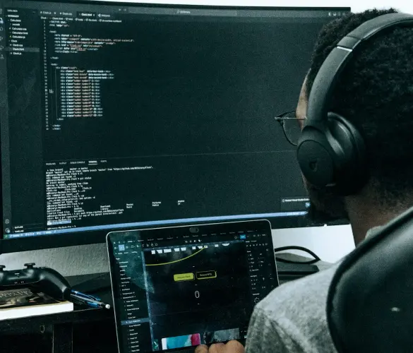 man writing programming code while wearing headphones